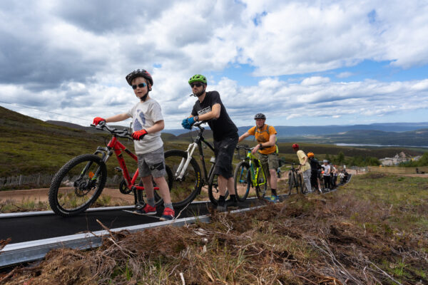 People with mountain bikes on conveyor uplift at Cairngorm Mountain
